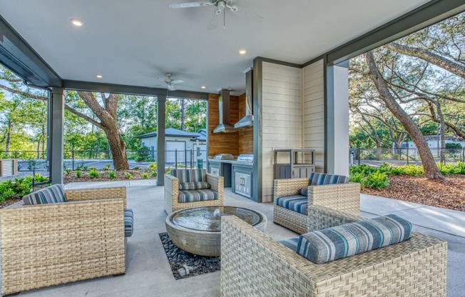 a covered patio with wicker furniture and a fire pit