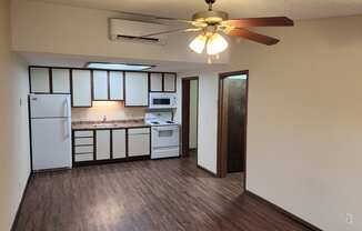 an empty kitchen with a ceiling fan and white appliances