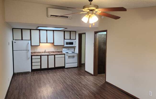 an empty kitchen with a ceiling fan and white appliances