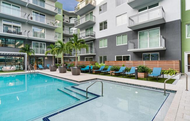 The resort-style pool features a sun shelf for in-water lounging, expansive deck space, and tropical landscaping that creates a relaxing outdoor retreat.