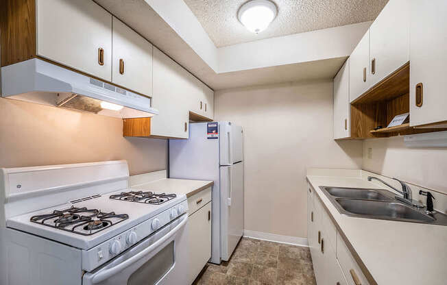 A galley-style kitchen with a white stove and refrigerator at Seville Apartments, Michigan