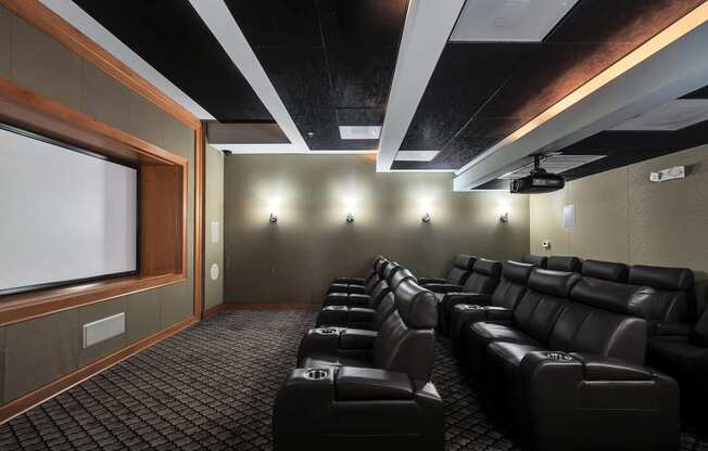 a large screening room with black leather seats and a projector screen