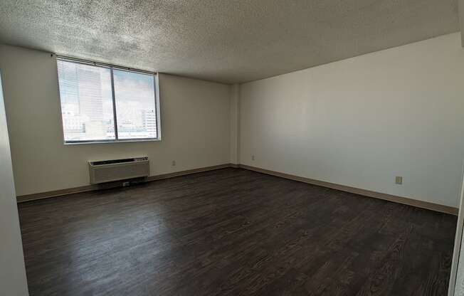 an empty living room with wood floors and a window