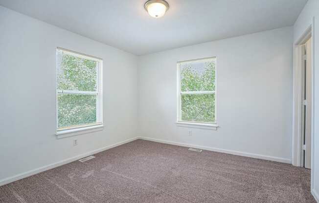 a bedroom with two windows and a carpeted floor