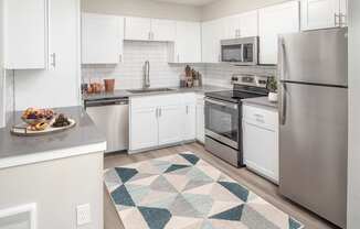 A kitchen with white cabinets and a rug on the floor.