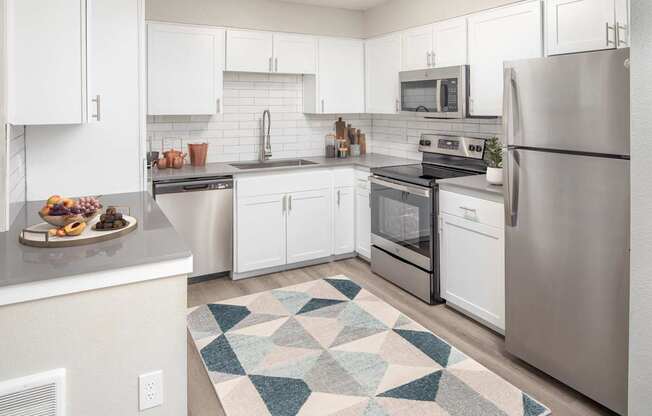 A kitchen with white cabinets and a rug on the floor.