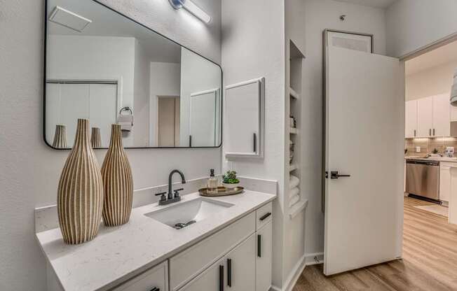 A bathroom with a sink, mirror, and vases.