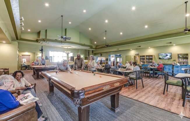 A group of people playing pool in a room with a pool table.