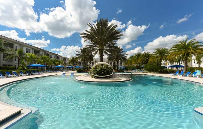 a large swimming pool with a fountain and a hotel in the background