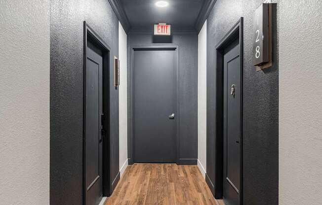 A hallway with doors on both sides and a sign above the middle door.