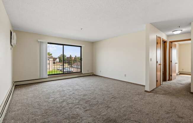 an empty living room with a large window and carpet