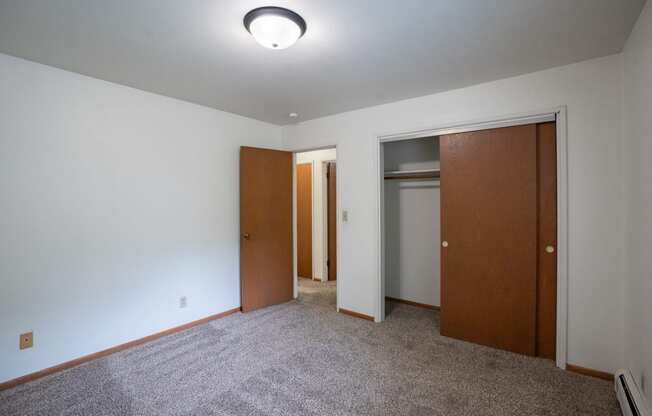 a bedroom with a closet and a door to a bathroom.  Fargo, ND Crown Court 1 Apartments