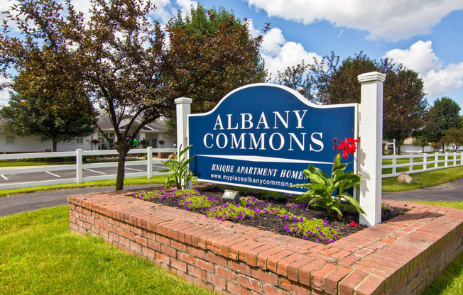 the sign commons in front of a brick retaining wall with flowers