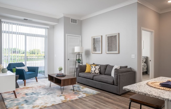 a living room with a couch and a chair and a table at The Edison at Maple Grove, Maple Grove, MN 55129