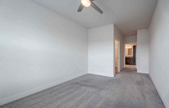 A room with a carpeted floor and a ceiling fan.
