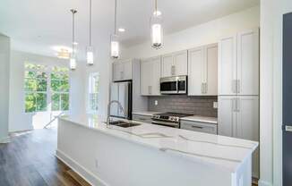 A modern kitchen with white countertops and stainless steel appliances.