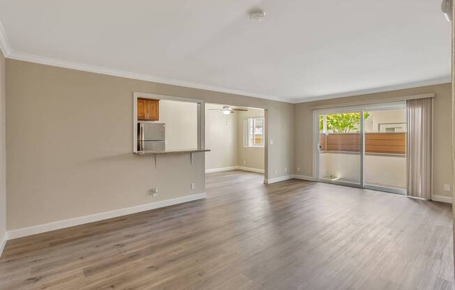 A spacious room with wooden flooring and a refrigerator built into the wall.