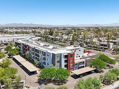 A large building with a red door is surrounded by trees.