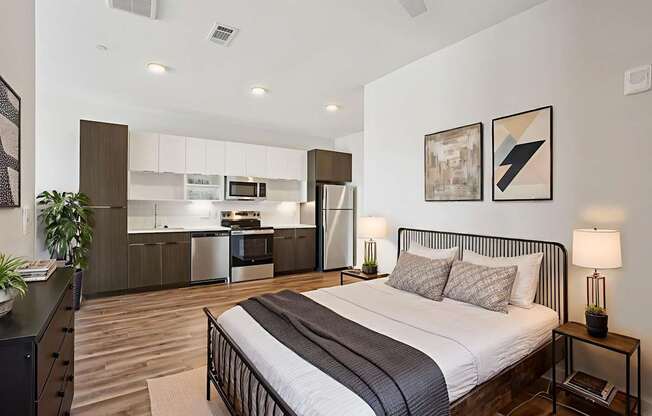 A bedroom with a bed, nightstand, and a plant.