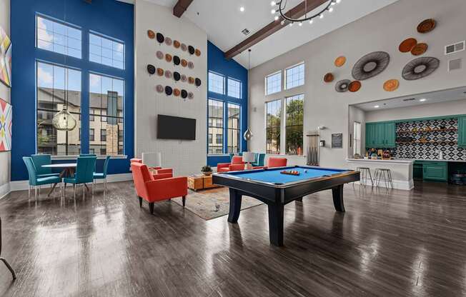 A pool table is in the middle of a room with a blue wall and a television.