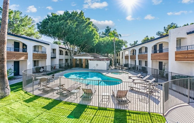 A sunny day at a resort with a pool and lounge chairs.