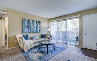 A living room with a couch, a coffee table, and a painting on the wall.