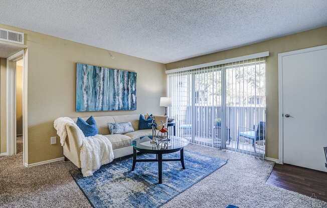 A living room with a couch, a coffee table, and a painting on the wall.
