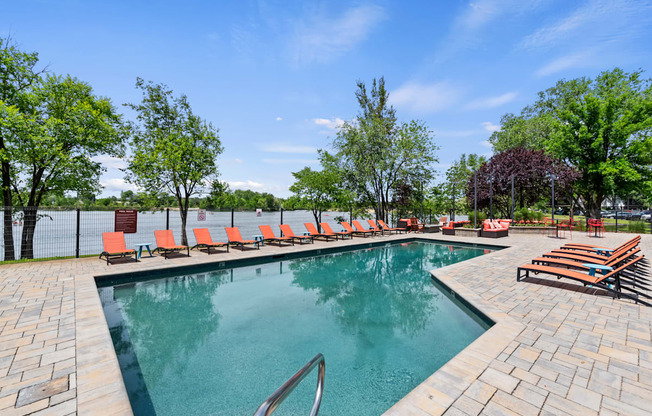 A pool surrounded by trees and chairs.