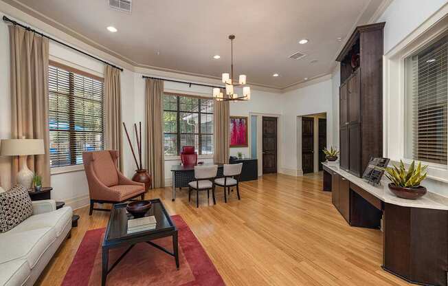 A living room with a white sofa, a brown chair, a black coffee table, and a red rug.