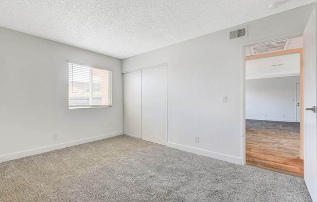 A room with a carpeted floor and a window with blinds.