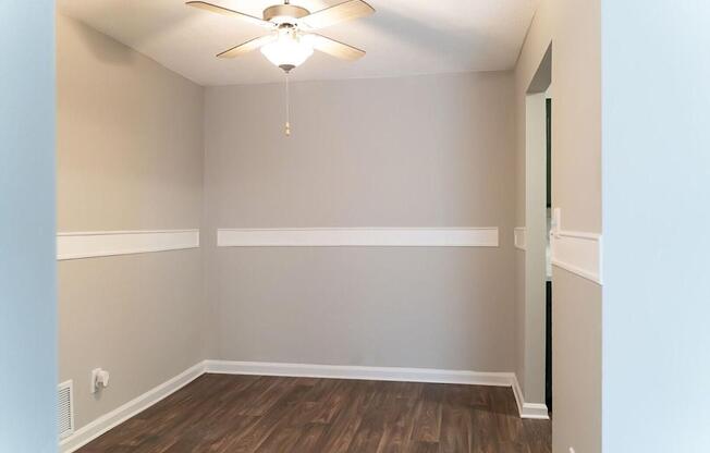 A room with a ceiling fan and wooden flooring.