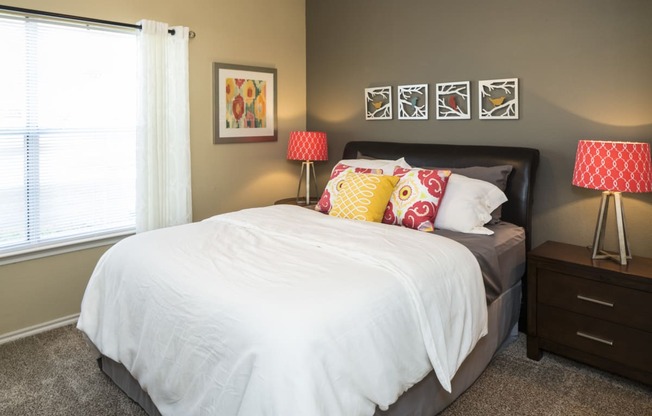 a bedroom with a large bed with a white comforter and colorful pillows