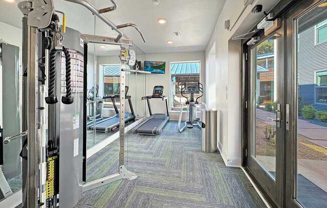 a gym with cardio equipment and a glass door