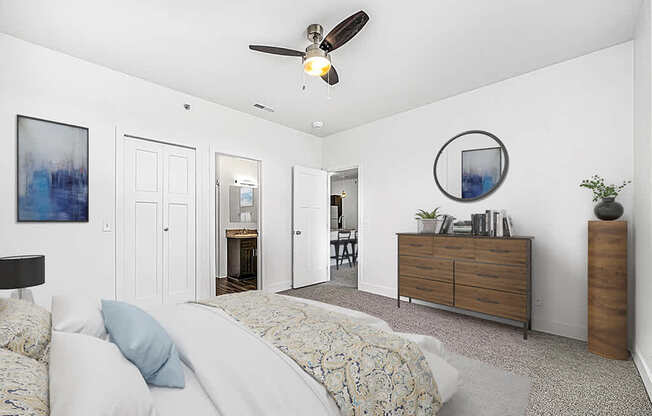A bedroom with a bed, dresser, ceiling fan and ensuite at Copper Creek Apartment Homes, Maize, Kansas