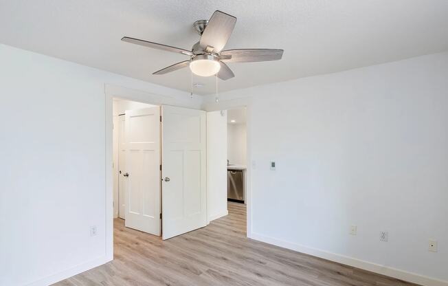 a bedroom with white walls and a ceiling fan