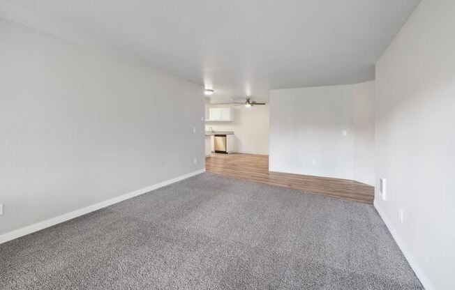 the living room and dining room of a house with white walls and carpet