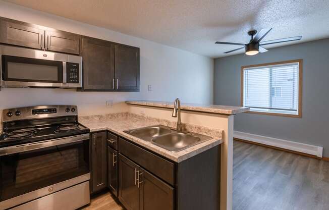 an empty kitchen with a sink and stove and a window. Fargo, ND Sunwood Apartments