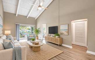 Virtually staged living room with a vaulted ceiling, exposed beams and sliding balcony doors at Waterchase Apartments in Largo, FL.