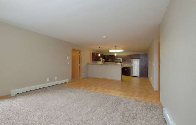 an empty living room and kitchen with a hard wood floor. Fargo, ND Urban Plains Apartments