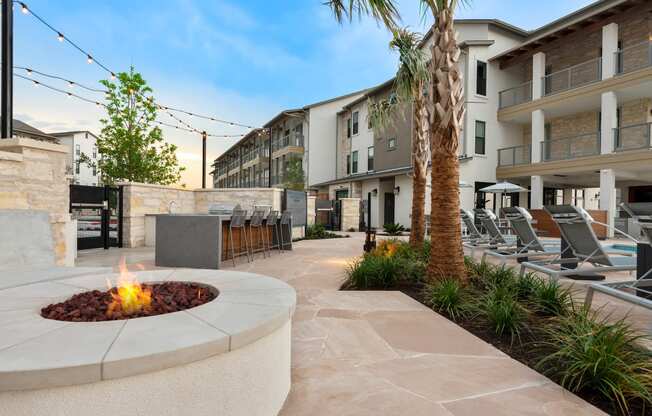 an outdoor patio with a fire pit and lounge chairs