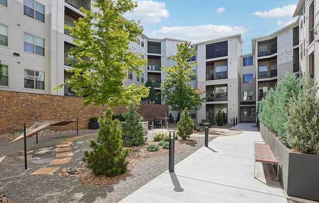 A courtyard with a bench and a tree in front of apartment buildings.