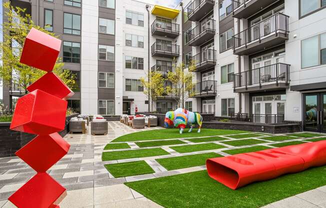 an apartment courtyard with a large red sculpture in front of an apartment building at Link Apartments® Mint Street, Charlotte, North Carolina