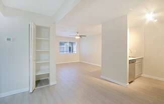 an empty living room with a kitchen in the background