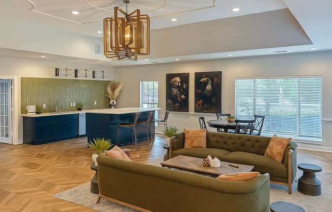 A living room with a green couch and a chandelier.