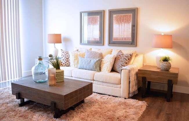 A living room with a couch, two lamps, and two pictures on the wall.