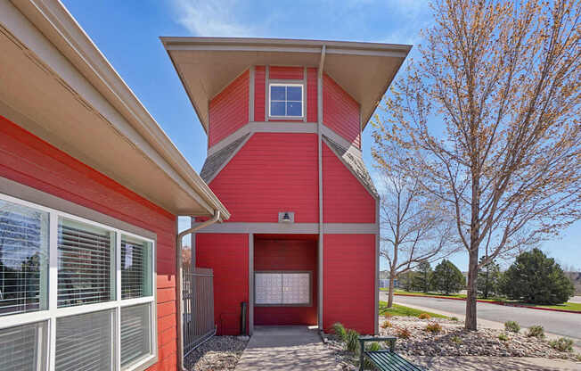 A red house with a white roof and a green bench in front.
