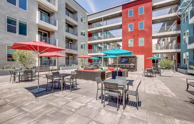 A patio with tables and chairs and umbrellas.