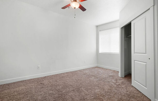 a bedroom with a ceiling fan and a closet