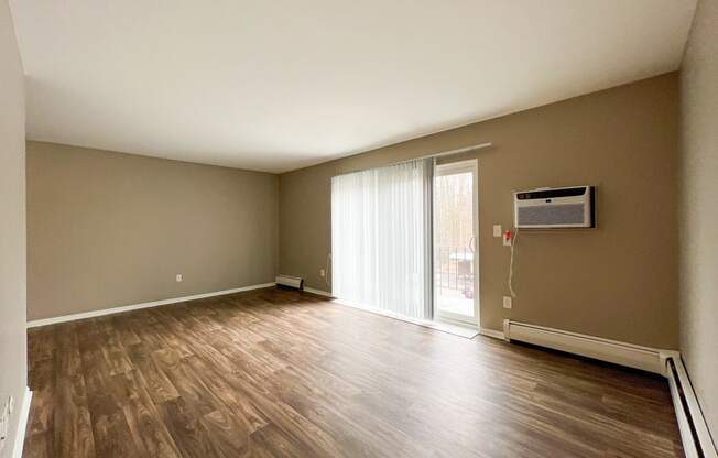 an empty living room with hardwood floors and a sliding glass door