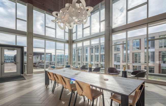 Interior resident lounge with floor to ceiling windows, large table, and artistic light features